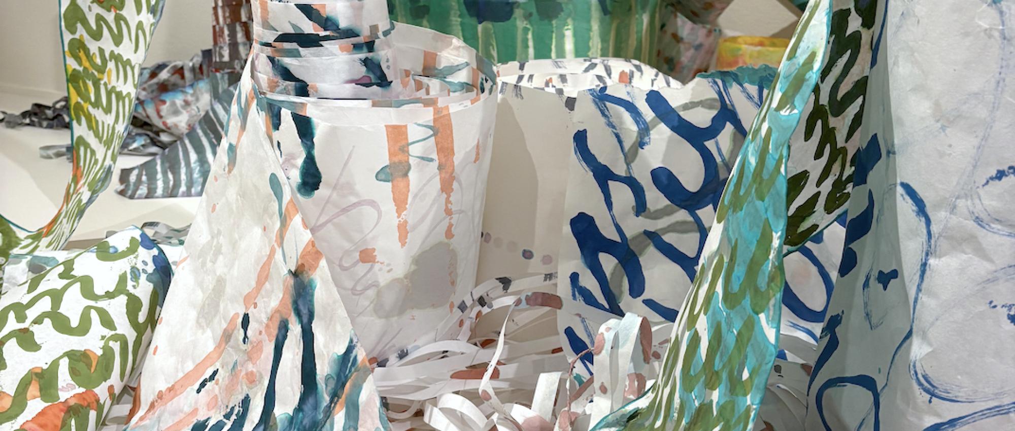 scrolls and rolls of paper are marked with hand-painted calligraphic lines in bright colors